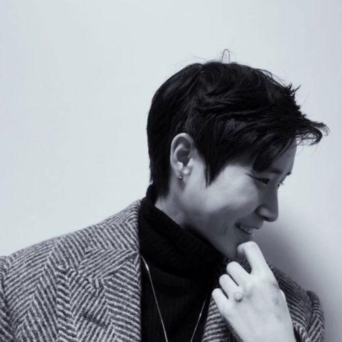 Smiling person in herringbone coat, monochrome photo.