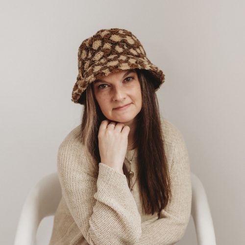 Woman wearing hat sitting on a chair.